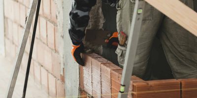 Bricklayer installing brick masonry on interior wall. Bricklayer installing brick masonry on interior wall.